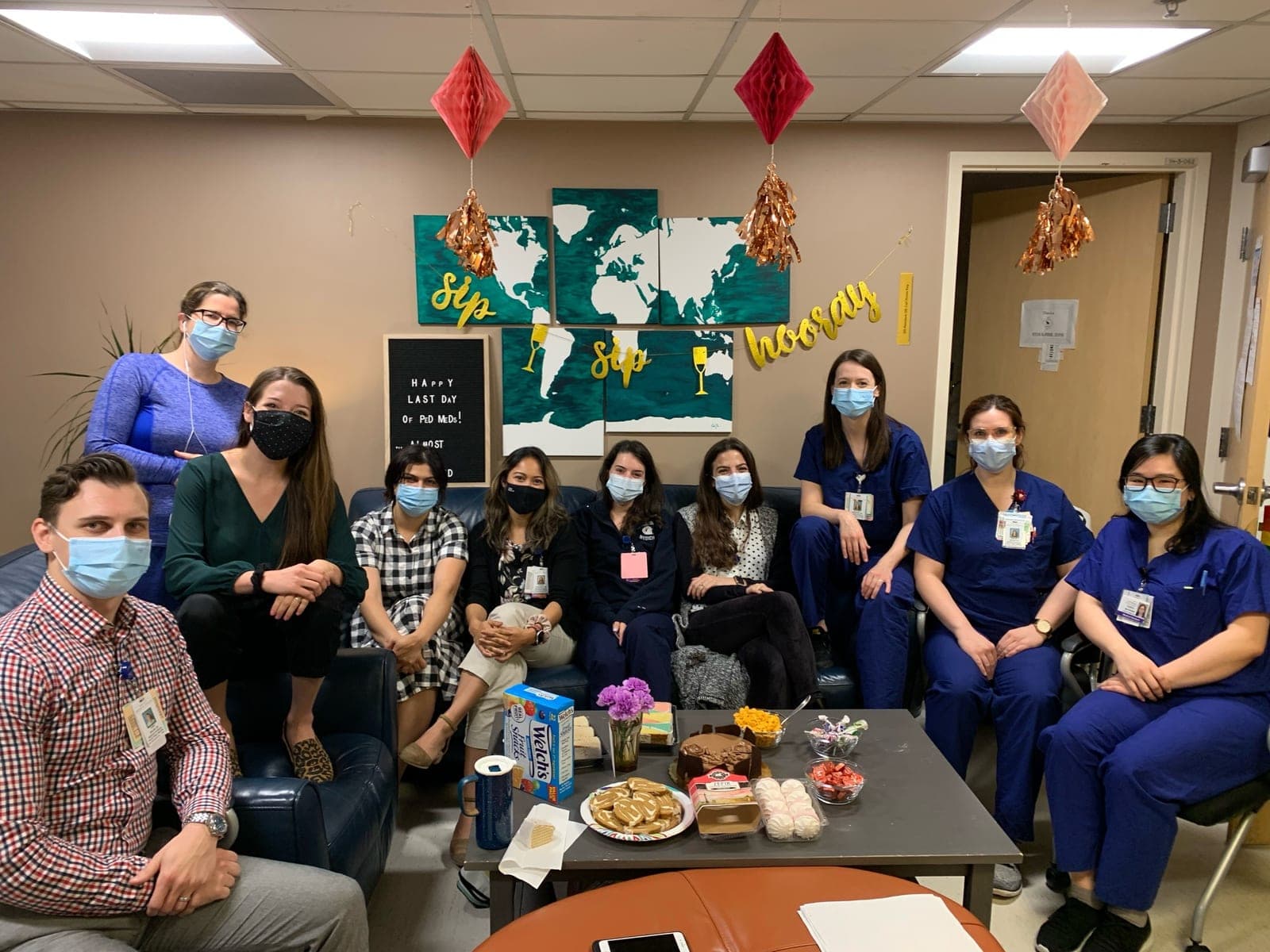 Residents and faculty of the inpatient team, in masks and scrubs, gathered in a decorated team room