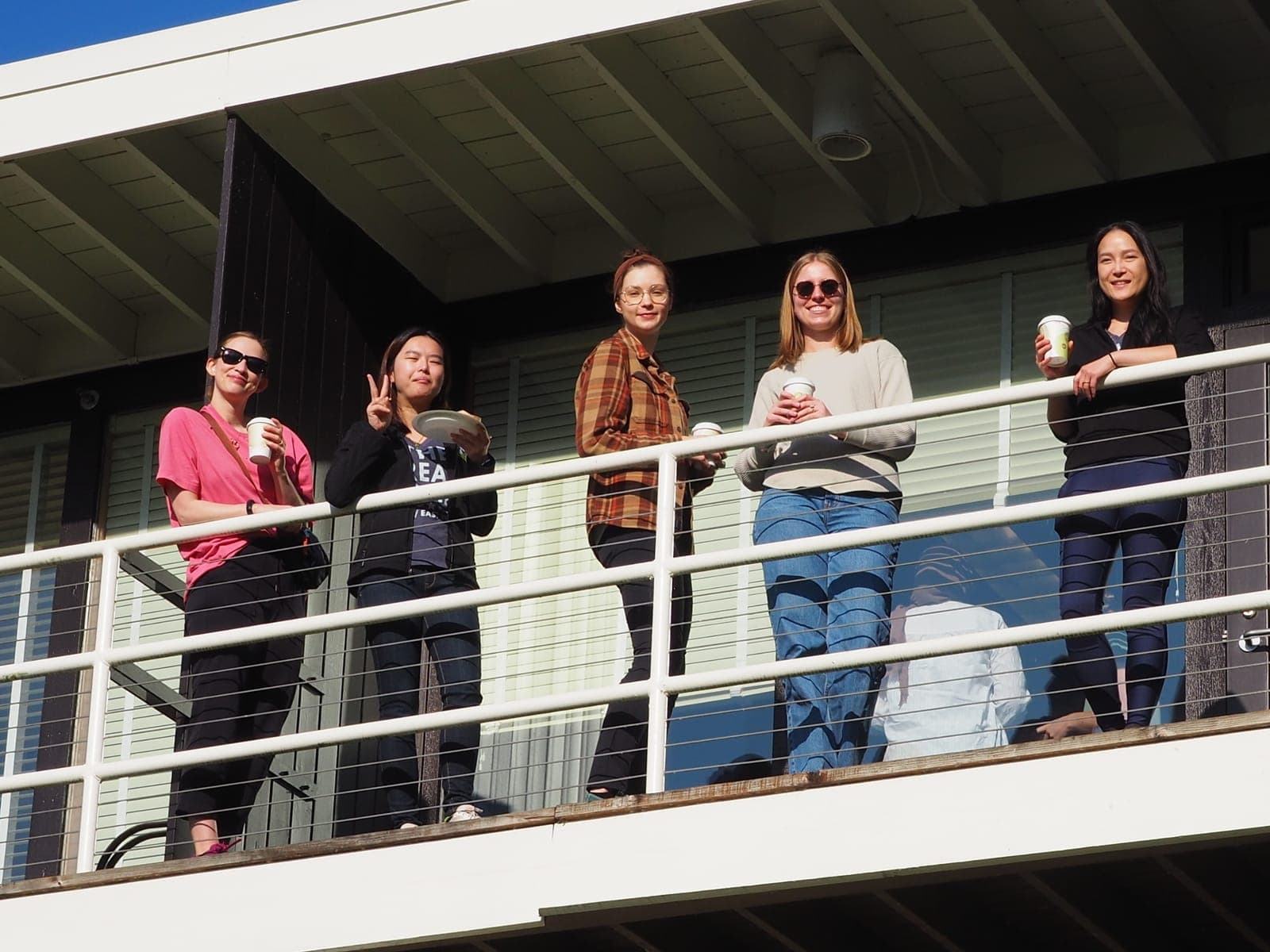 Residents chatting and holding drinks on a cabin balcony