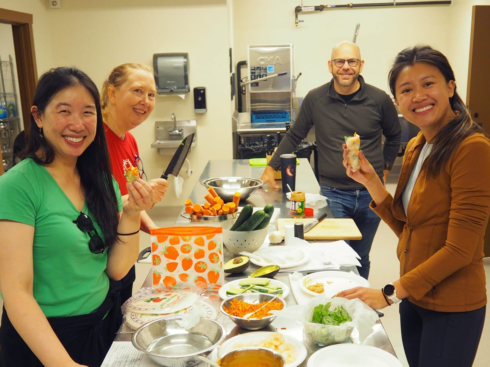 Residents and faculty holding up food they prepared in a kitchen