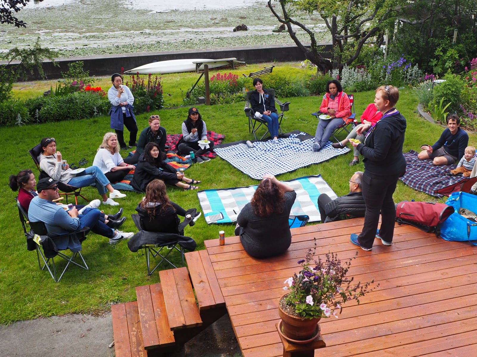 Residents sitting in a circle of camp chairs and blankets on a lawn, listening to a speaker