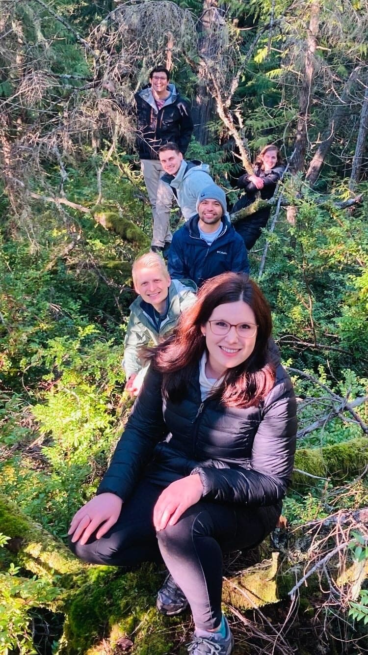 Third-year residents smiling on a forest hillside surrounded by ferns and moss