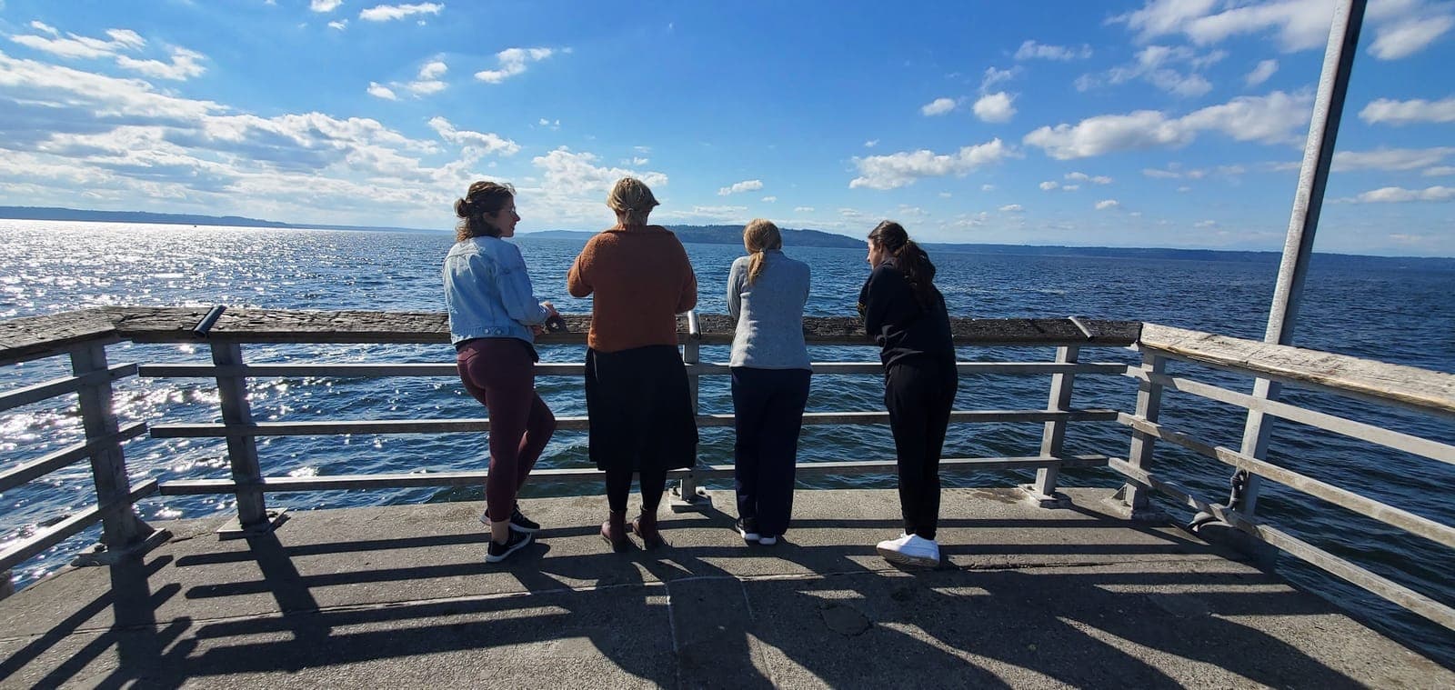 Residents standing at the railing of a pier looking out over sparkling water