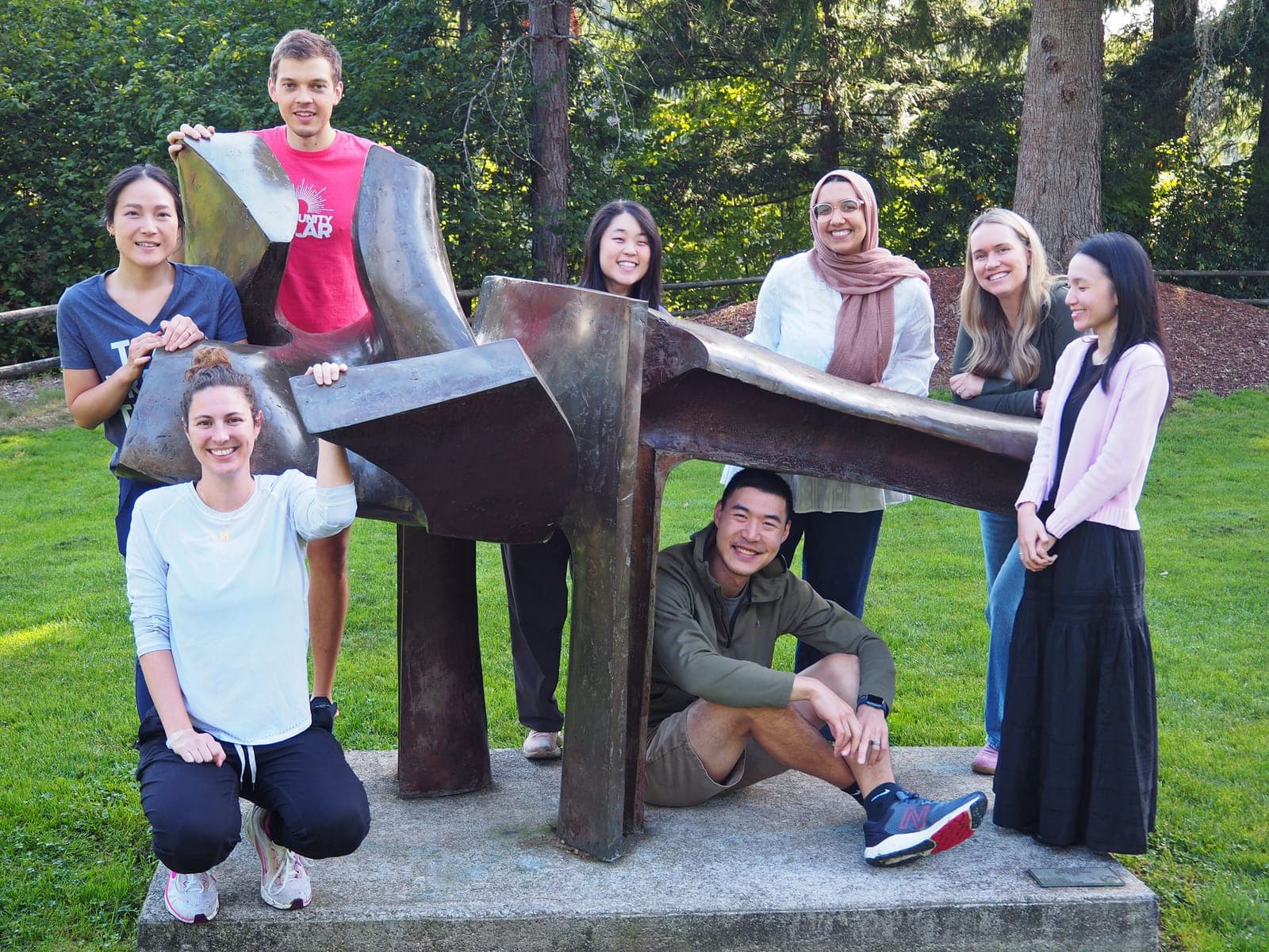 Residents from the class of 2026 posing around a bronze sculpture on a lawn