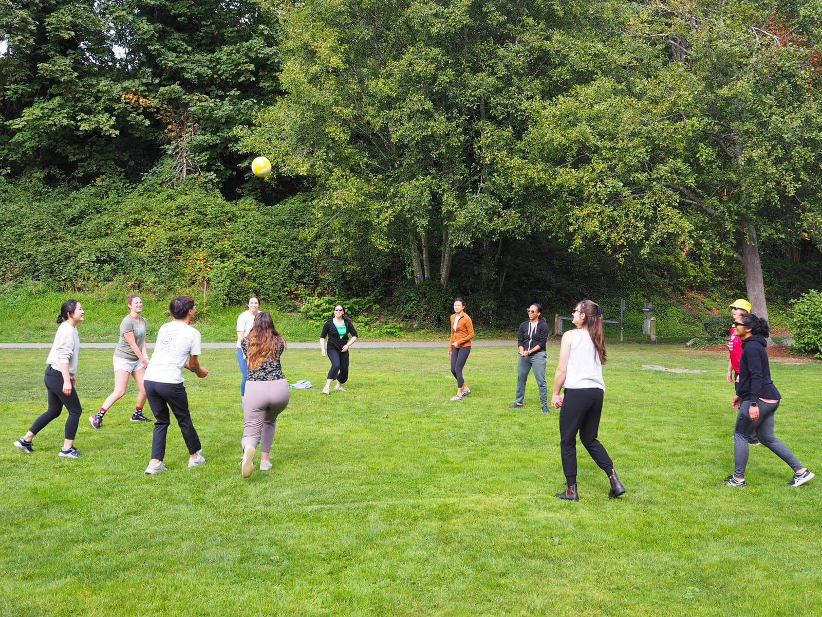 Residents playing volleyball in a circle on a grassy field