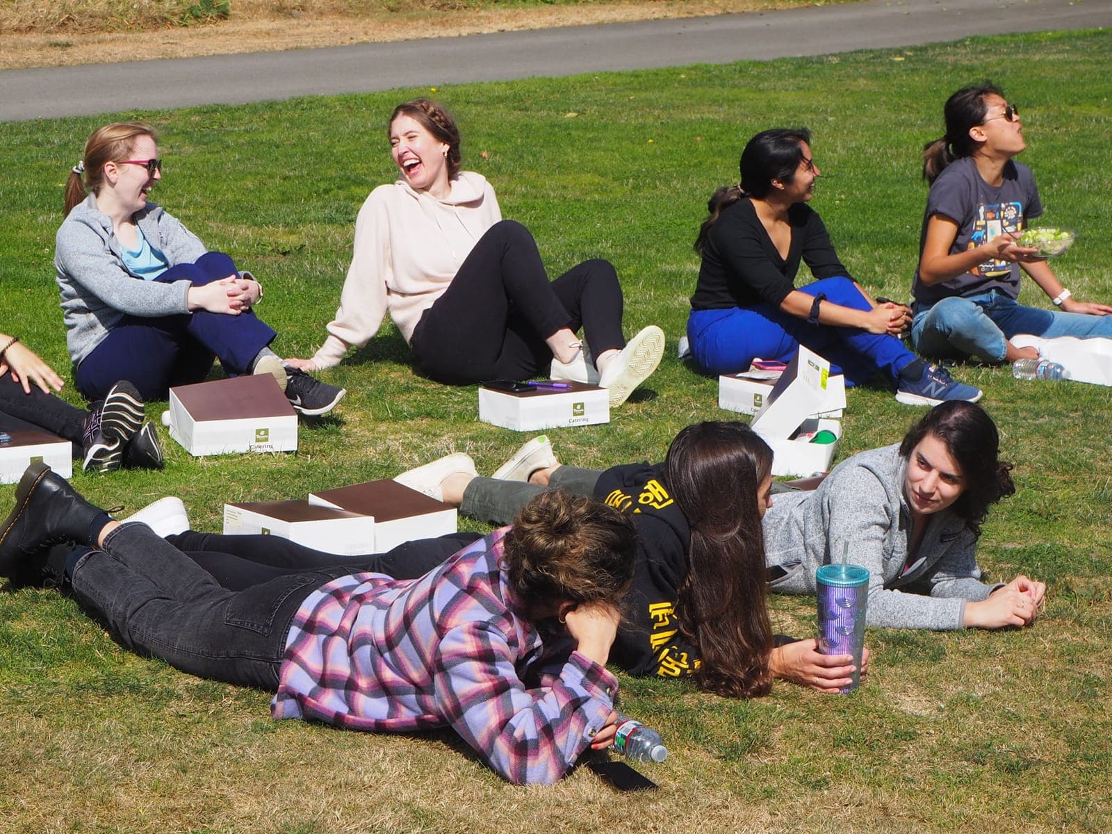 Residents sitting and lying on the grass, laughing while they watch a game