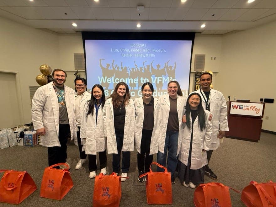 New residents in white coats in front of a welcome slide