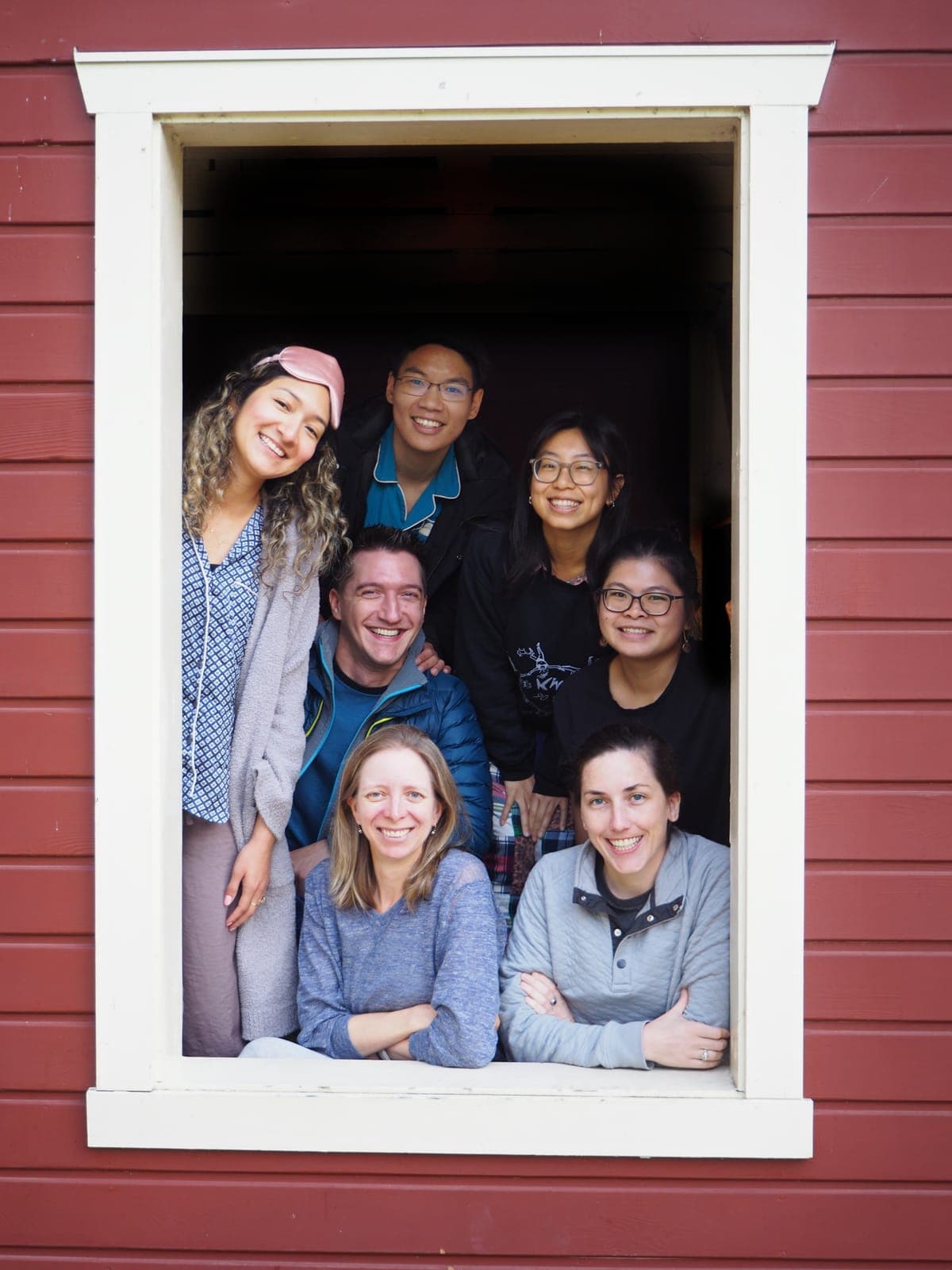 Residents from the class of 2025 crowded into the window frame of a red cabin