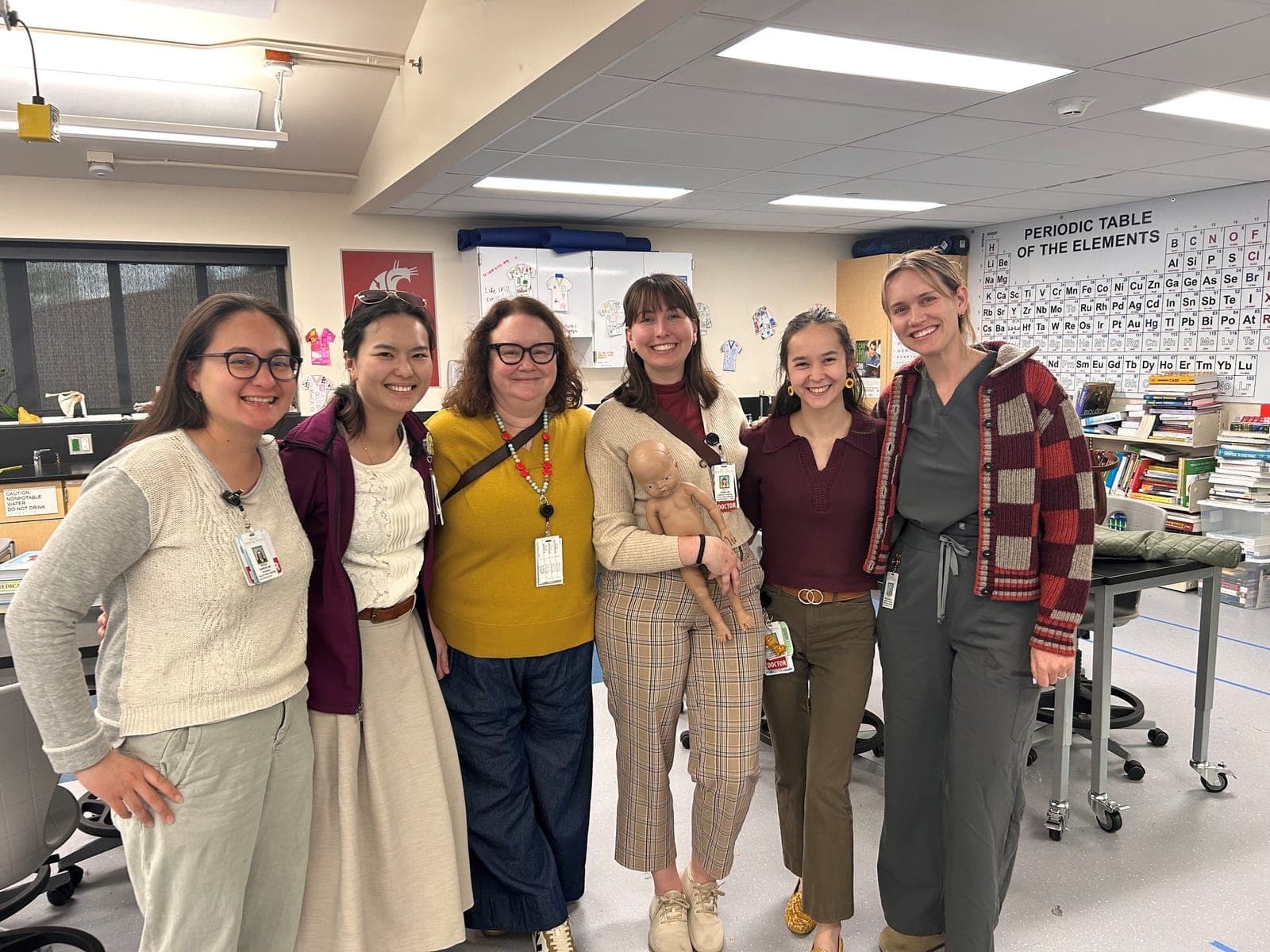 Six residents and faculty standing together in a high school science classroom