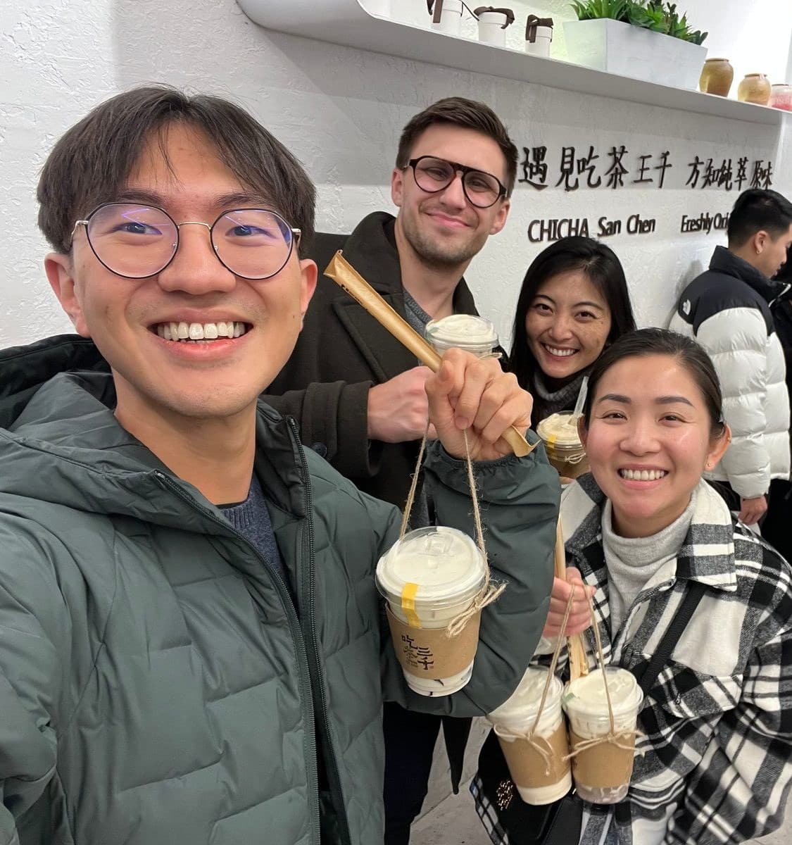 Four residents holding up cups of milk tea inside a tea shop