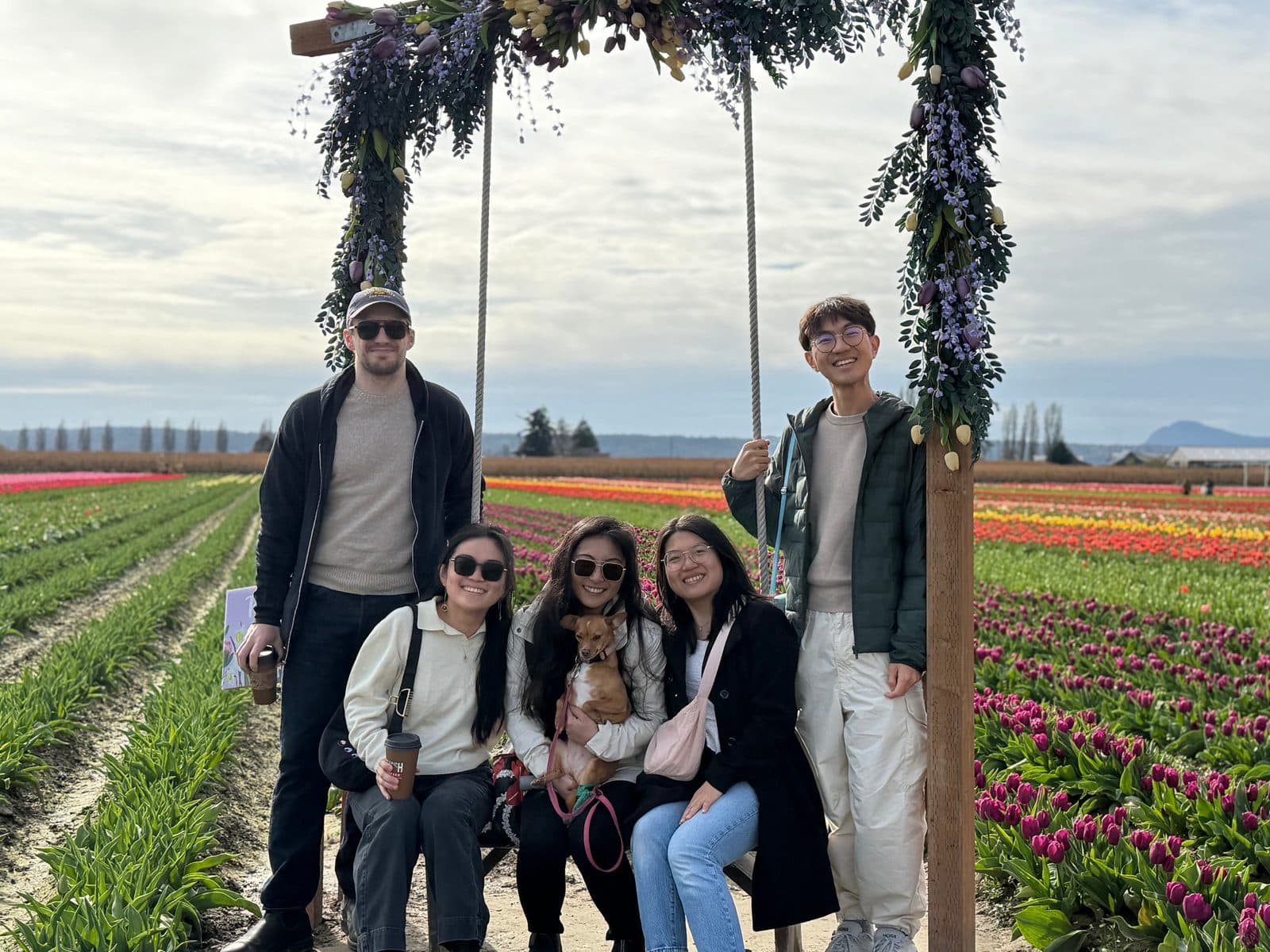 Residents and a small dog on a flower-covered swing among rows of tulips at the Skagit Valley Tulip Festival