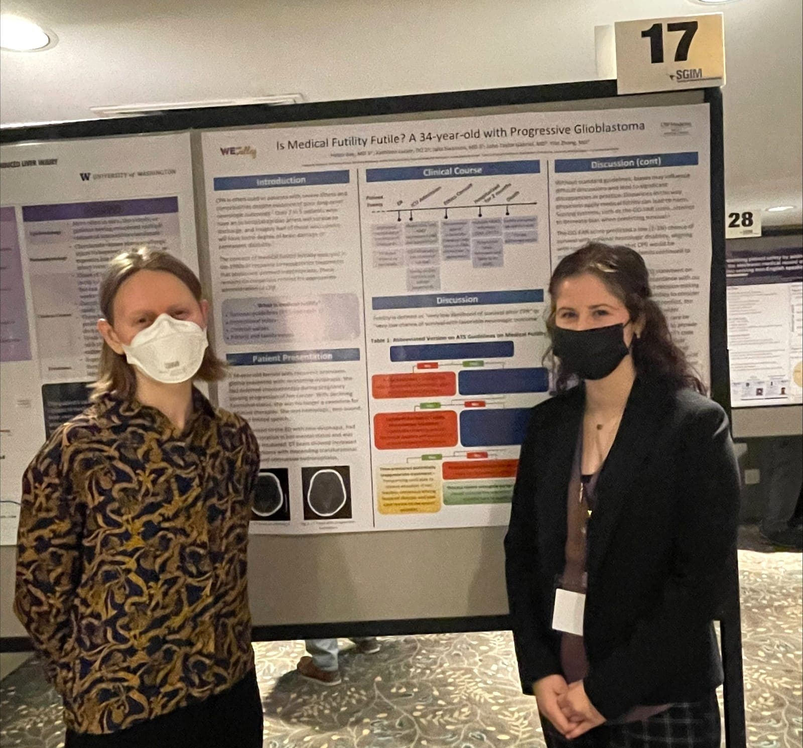 Two residents in masks standing beside their case poster