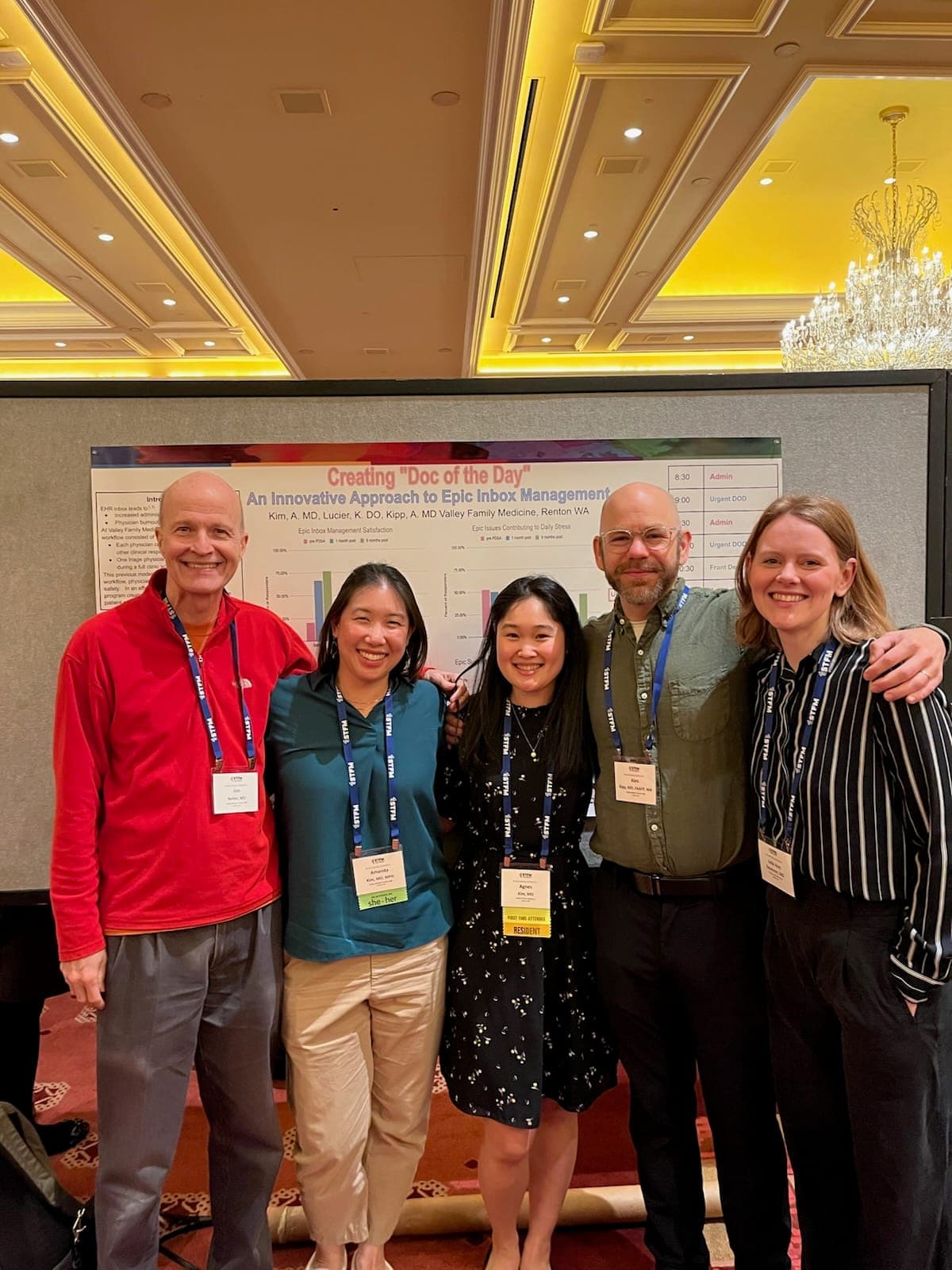 Five faculty and residents smiling together in a hotel ballroom