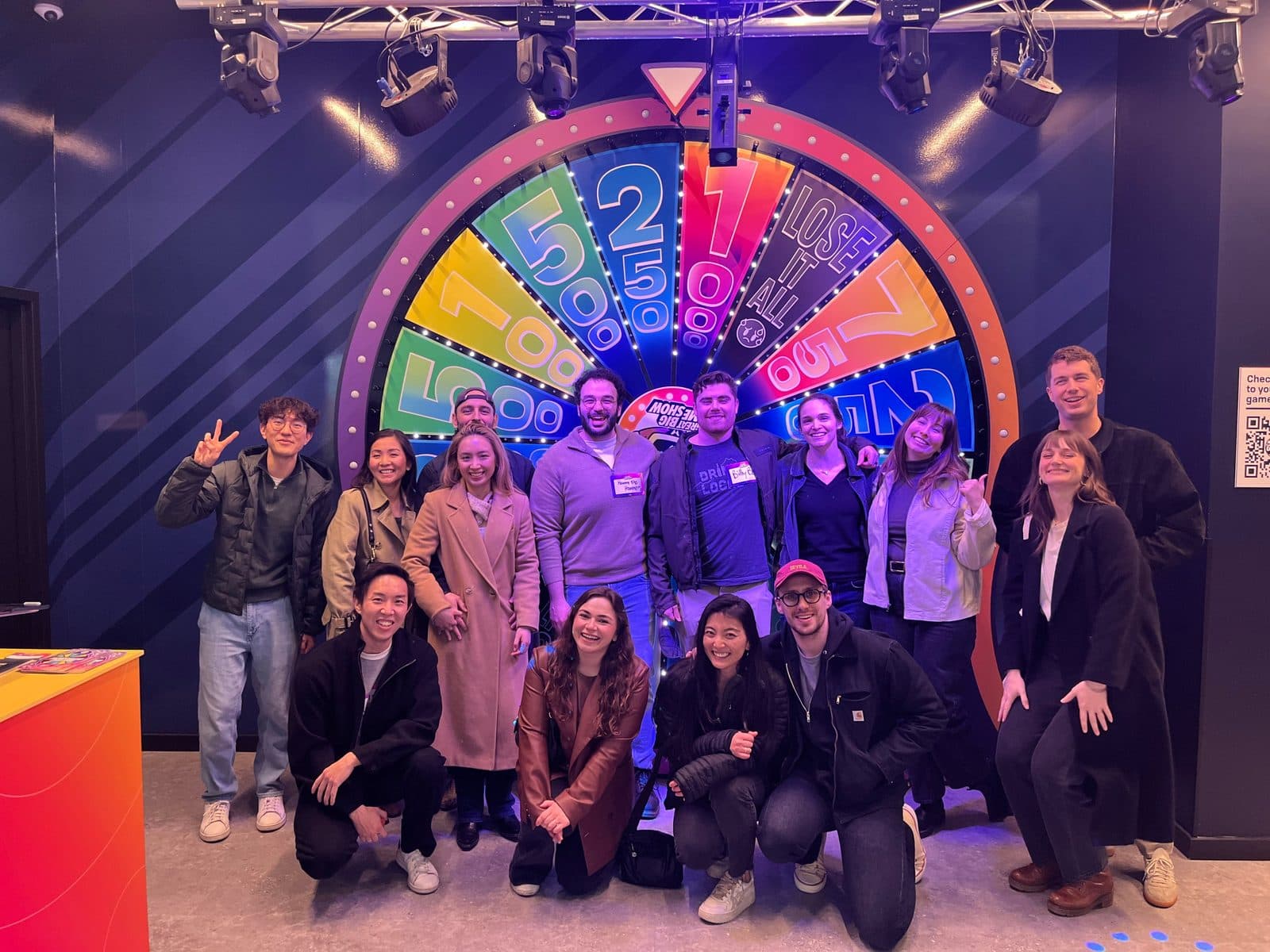 Residents from the class of 2027 posing in front of a giant colorful prize wheel at a game night