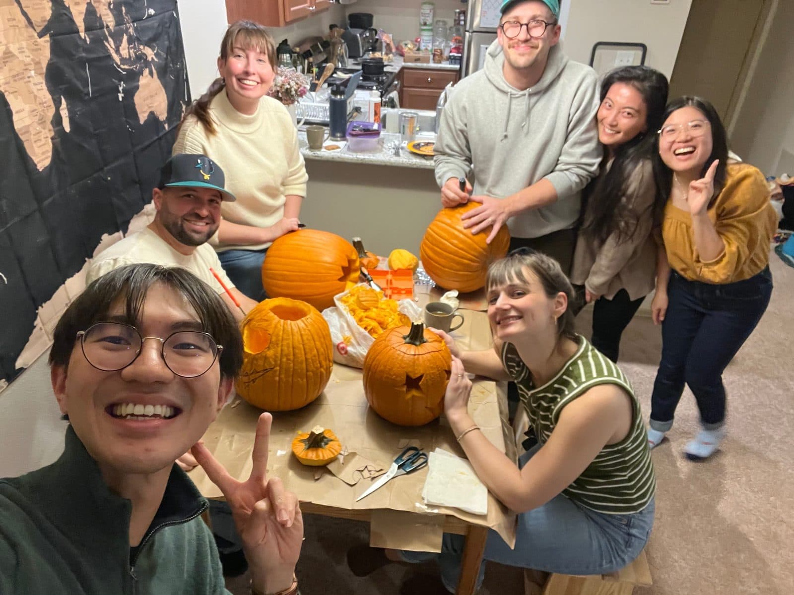 Residents from the class of 2027 carving pumpkins around a kitchen table