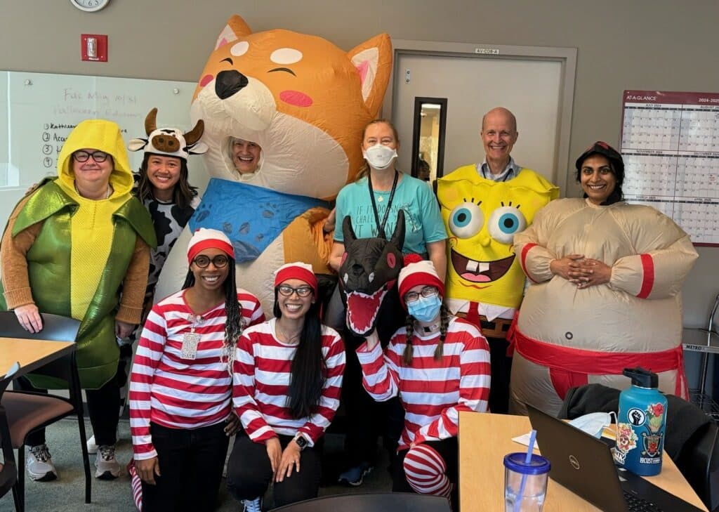 Faculty and residents in Halloween costumes, including an inflatable shiba inu, SpongeBob, an ear of corn and a group of Waldos