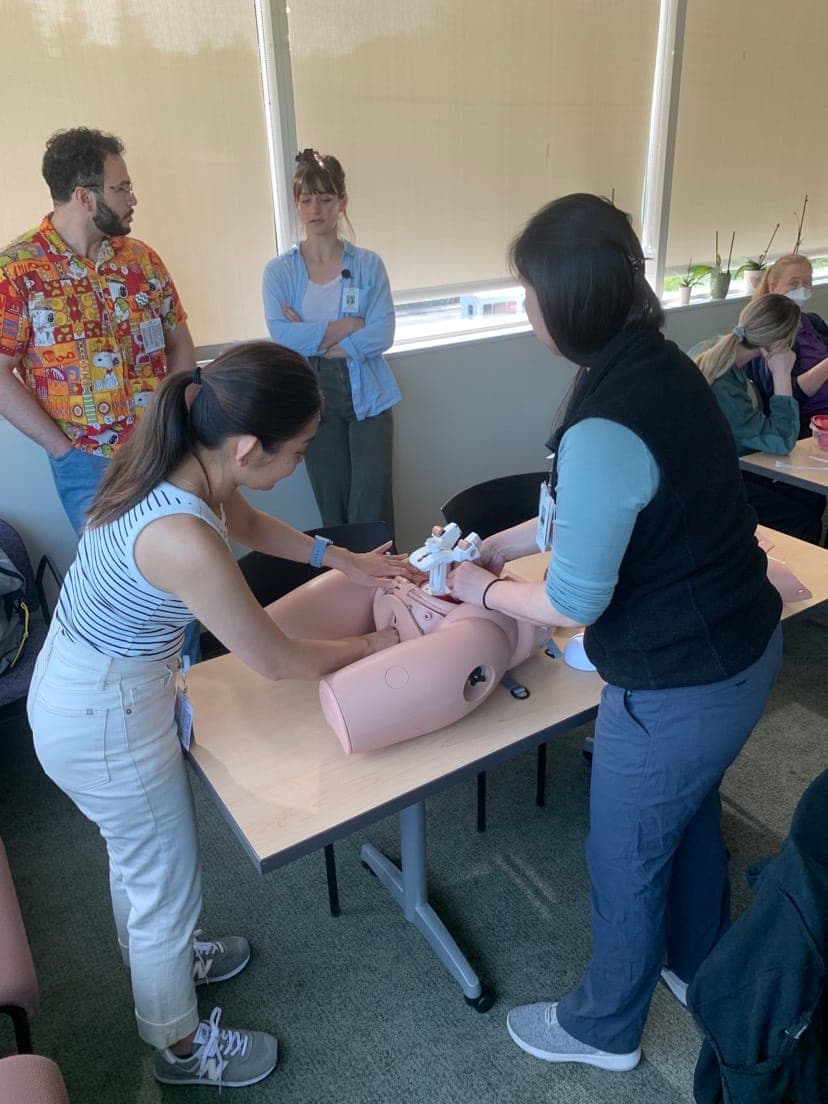 Residents practicing a delivery on an obstetric simulation model with faculty
