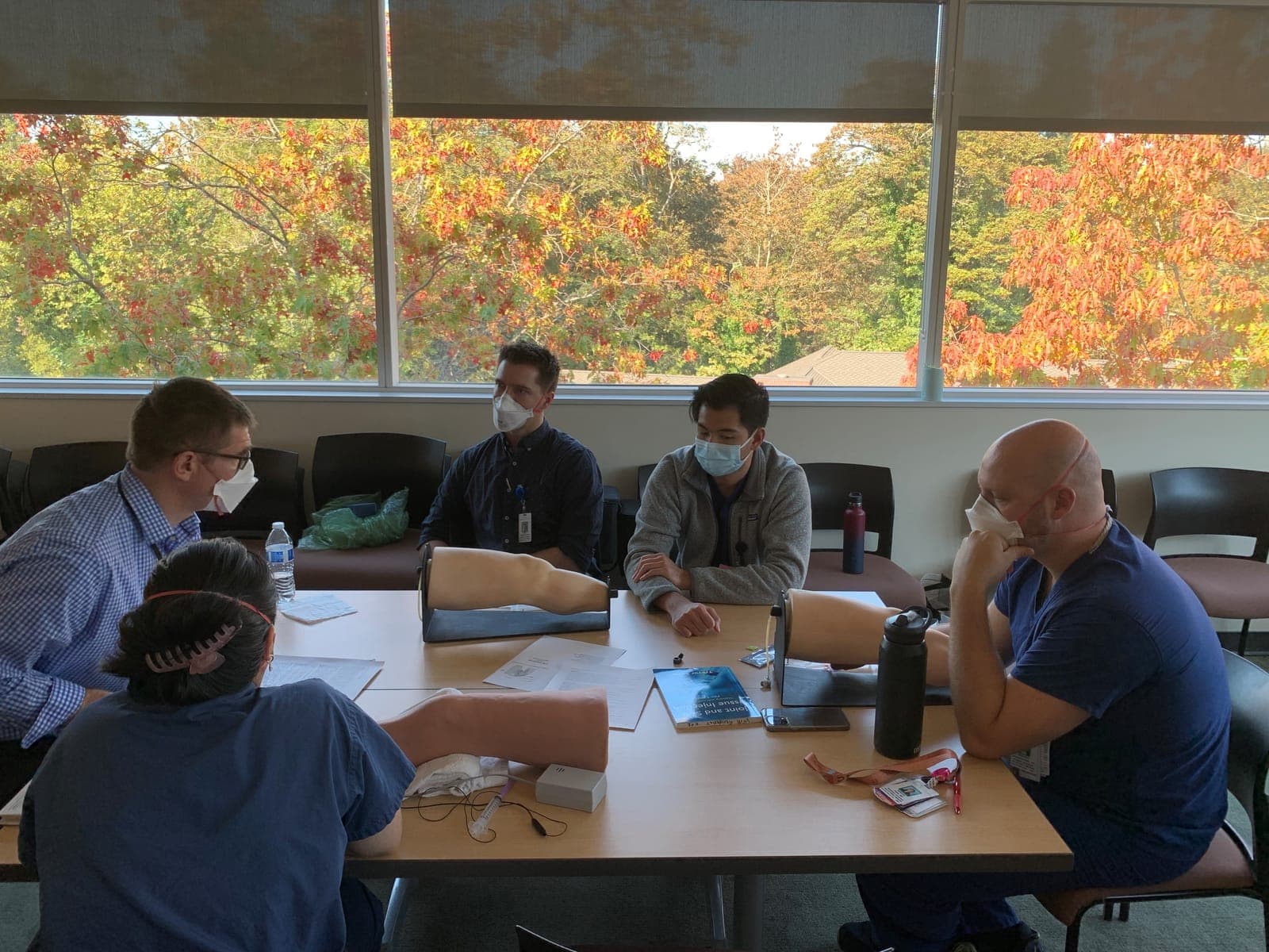 Residents and faculty around a table practicing injections on knee and shoulder models
