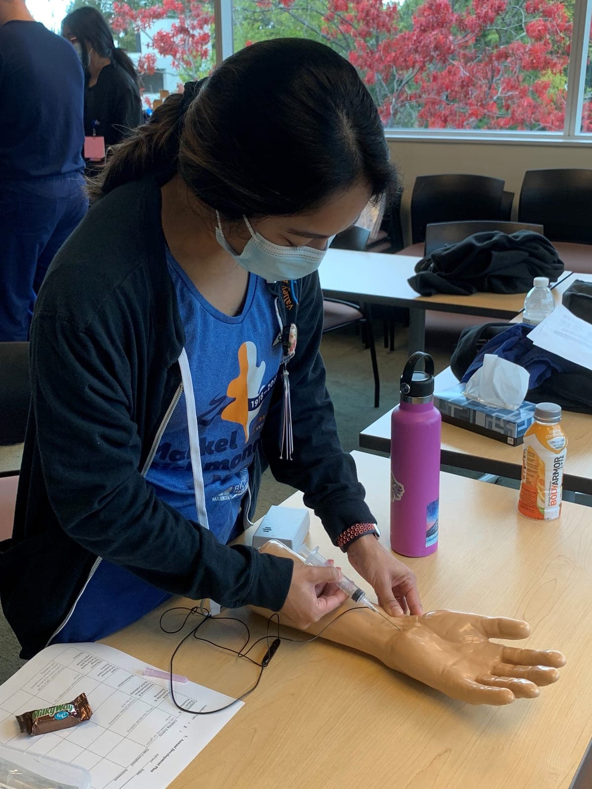 A resident practicing an injection on a hand and wrist model