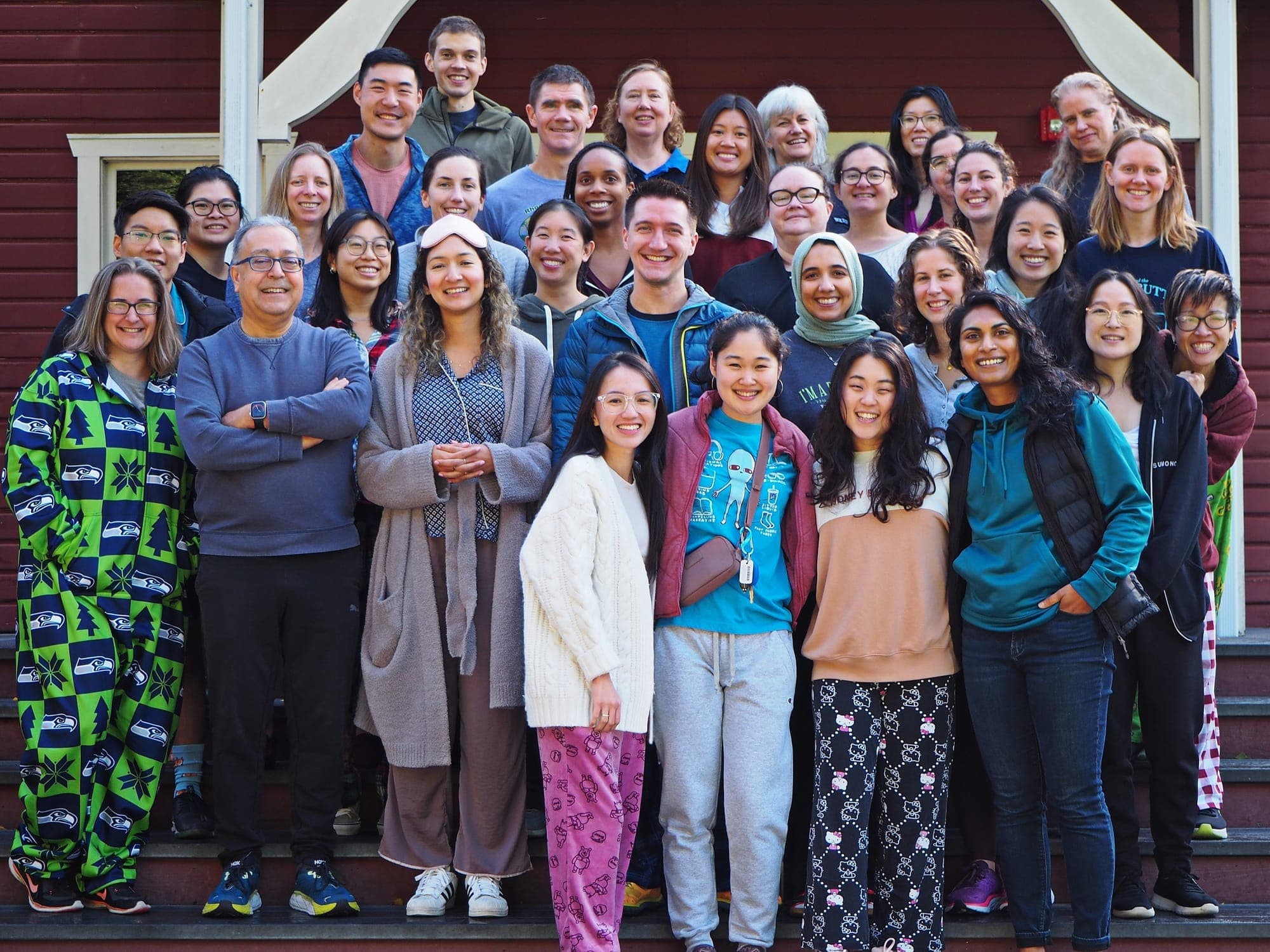 Residents and faculty, some in pajamas, gathered on the steps of a red wooden lodge