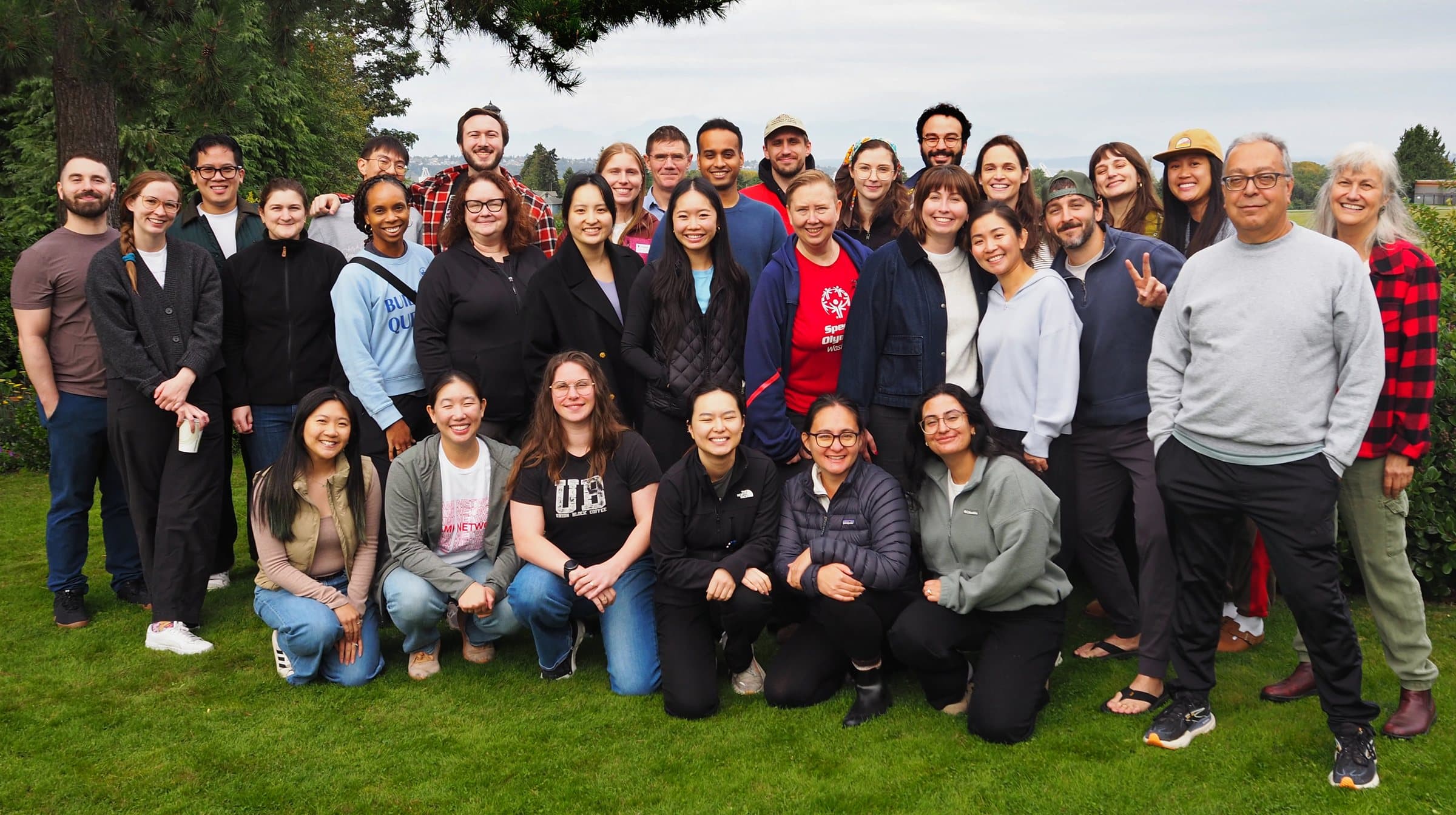 Valley Family Medicine residents and faculty standing together on a lawn under evergreen trees